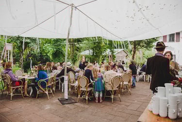 Wedding guests sitting at tables underneath a tarp.