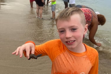 a young boy is holding a fish in his hand