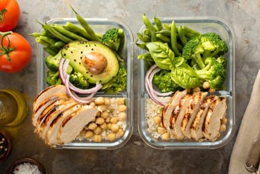 Healthy meal prep containers with grilled chicken, avocado, broccoli, and green beans.