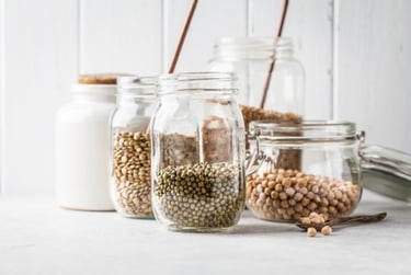 Variety of dried legumes including mung beans and chickpeas stored in glass mason jars for a plastic-free pantry.