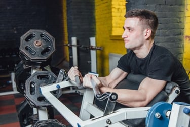 A man performing bicep curls on a preacher curl machine at a fitness gym for strength training.