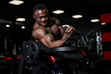 Muscular bodybuilder performing bicep curls on a preacher curl machine in a gym.