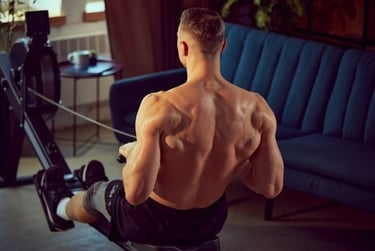 Muscular man using a rowing machine in a home gym setting to build back strength.