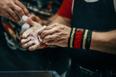 A weightlifter with wrist wraps applying white gym chalk to hands for a secure grip during a workout.