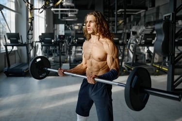 Muscular long-haired man performing barbell bicep curls for strength training in a modern gym.