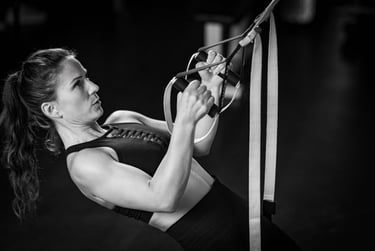 A woman performing a suspension trainer row exercise in a gym for strength training.