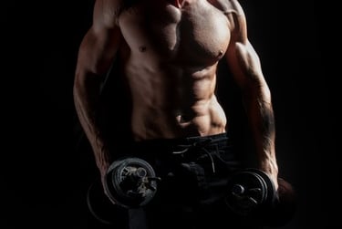 Muscular man with defined abdominal muscles holding heavy dumbbells for strength training.