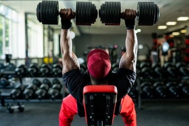 Muscular bodybuilder performing a heavy dumbbell bench press for chest strength training in a gym.