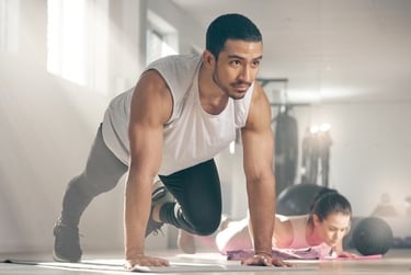 A fit man performing mountain climber exercises on a mat during a gym workout session.