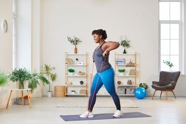 Smiling woman performing upright rows with a resistance band during an indoor home workout.