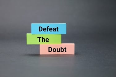 Stacked colorful blocks displaying the motivational phrase Defeat The Doubt against a dark background.