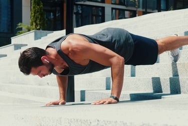 Athletic man performing incline pushups on outdoor city stairs for a strength training workout.