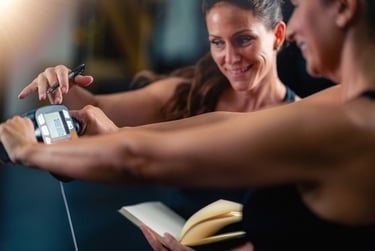 A personal trainer tracking body fat percentage for a female client using a digital body composition scale.