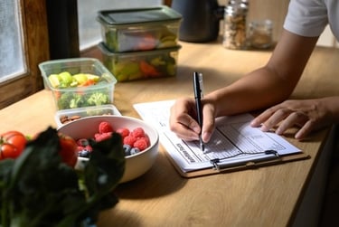 A person tracking healthy meal prep containers and nutrition facts on a clipboard.