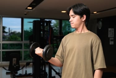 A young man performing bicep curls with a dumbbell during a fitness workout in a modern gym.