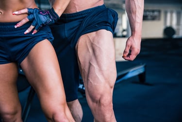 Close-up of muscular bodybuilder legs with defined quadriceps muscles and vascularity in a gym setting.