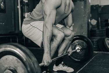 Muscular bodybuilder performing a heavy barbell deadlift in a gym during a strength training workout.