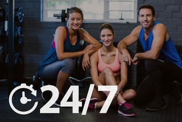 A group of smiling fitness members at a 24/7 gym representing around-the-clock health and exercise.