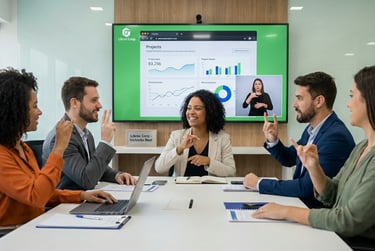 Equipe corporativa sorridente em reunião sinalizando em Libras, com tela ao fundo exibindo gráficos