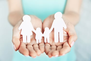 a woman holding two hands with paper cutouts of a family
