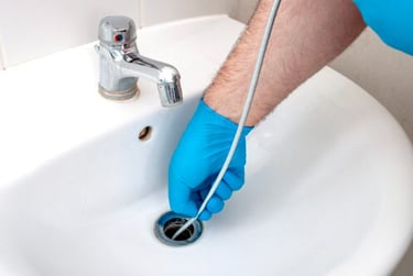 Using a drain snake to clean a clogged bathroom sink