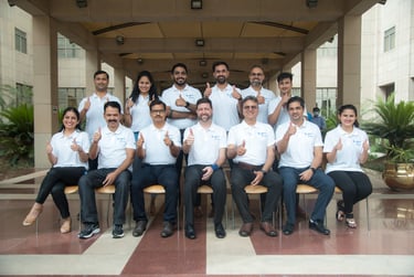 A diverse group of people smiles and gives thumbs-up signs in a team photograph.