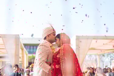 Bride and groom in traditional wedding attire share a tender moment with falling petals.