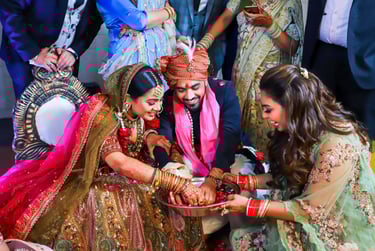 A bride and groom participate in a wedding ritual, their hands together over a bowl, while a woman s