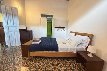 Rustic bedroom with patterned tile floors, wooden bed frame, and vintage white doors.
