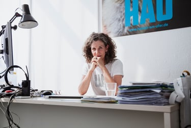 Annemie Vanackere photographed in her HAU office behind a desk.