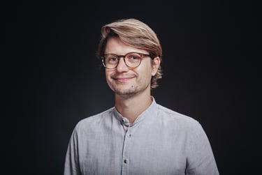 CV portrait in a studio with a black background.