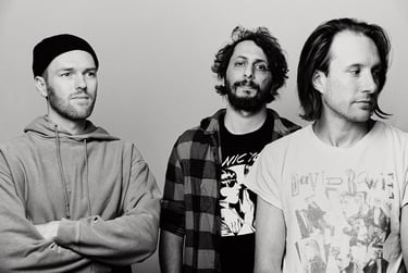 Schwarz-Weiß-Porträt einer dreiköpfigen Band.