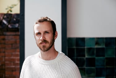 Das Porträt eines jungen Mannes in einem weißen Pullover.