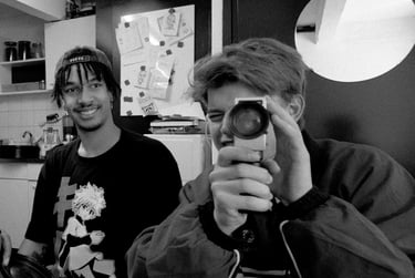 Youth looking through a Super8 film camera with his friend watching.
