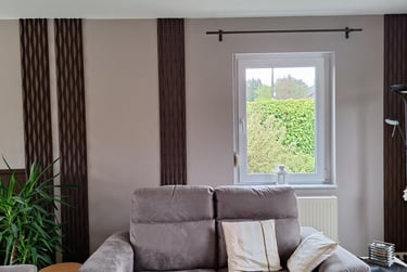 Réalisation d'un living avec des panneaux décoratifs bruns sur un mur beige avec un canapé