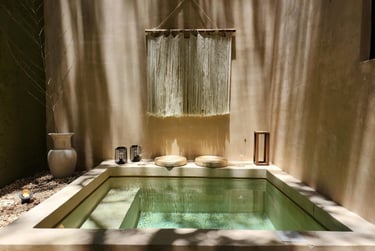 Luxury private plunge pool with boho macrame wall hanging and stone seating in a sun-drenched courtyard.