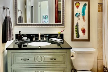 Bathroom with vintage emerald vanity, black granite countertop, and beveled glass mirror.