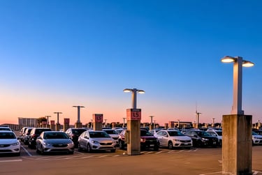 Rooftop parking deck at sunset with cars lined in Level 5 East under orange and blue sky.