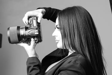 Professional female photographer holding a DSLR camera with a large lens in a studio setting.