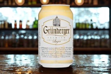 Can of Grünberger Premium Lager beer on a wooden bar counter with a blurred background.