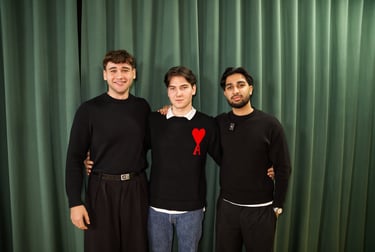 three men standing next to each other in front of a curtain
