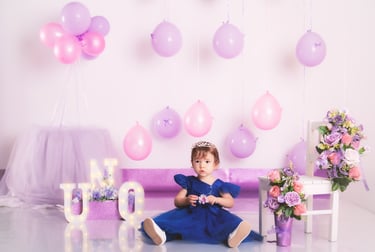 a little girl in a purple dress sitting on a couch