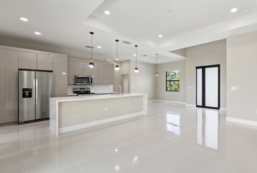 Open kitchen and living floor plan featuring bege cabinets