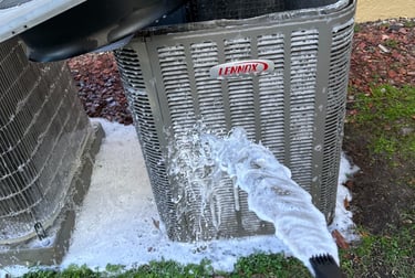 Professional HVAC technician spraying cleaning foam on an outdoor Lennox air conditioner unit for maintenance.