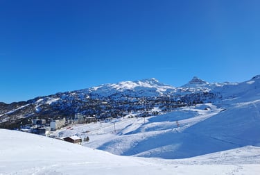 a person on a ski slope with a mountain in the background