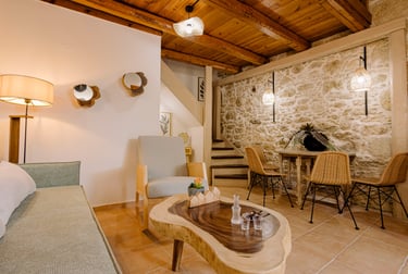 Rustic living room with stone wall, wood ceiling, and cozy seating area.