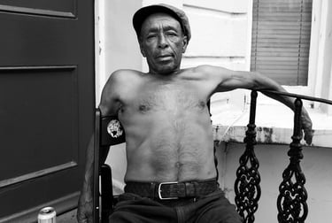A Caribbean man drinking and enjoying the summer weather on his porch in Notting Hill