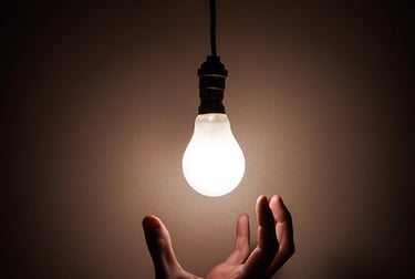 a person holding a light bulb in a dark room