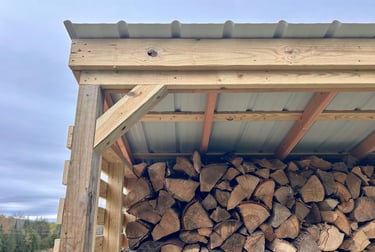 a chord of chopped wood logs stacked on top of each other in a wooden storage shed
