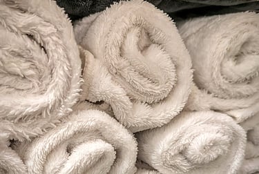 A stack of rolled white microfiber towels with a soft, plush texture for spa or bathroom use.
